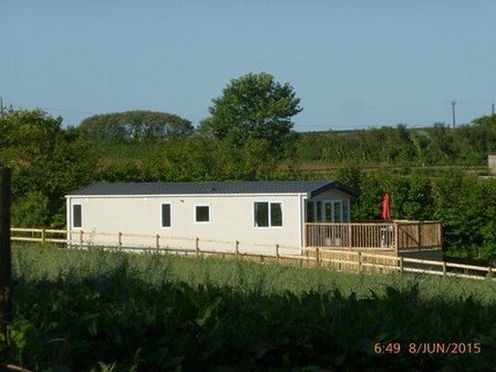 a holiday home with a wooden deck surrounded by greenery at Barnston Farm - Holiday Accommodation 3594 in Totnes