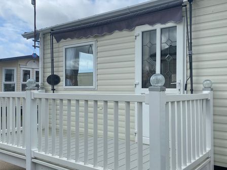 A doorway and windows on a deck at Happy Days Caravan Park - Holiday Accommodation 3599 Towyn