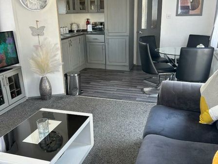 a living room with a sofa and glass dining table at Golden Sands Kinmel Bay - Holiday Accommodation 4446 in Rhyl