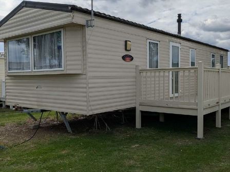 a mobile home with a deck and windows at Coopers Beach Holiday Park - Holiday Accommodation 4567, East Mersea