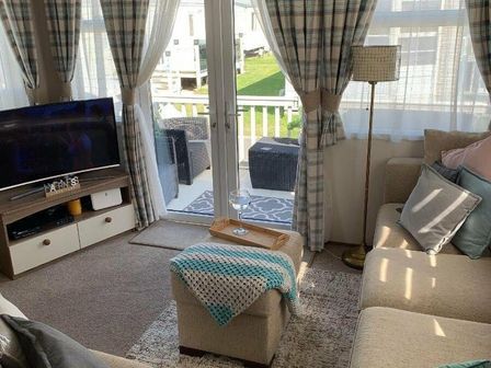 a living room with a TV, sofa, and curtains at Marine Holiday Park - Holiday Accommodation 4829 in Rhyl