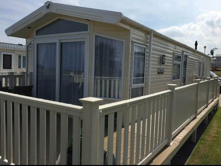 a caravan with a decking area at Reighton Sands Holiday Park - Holiday Accommodation 5068, Filey