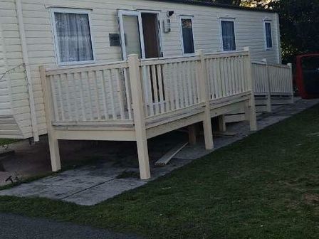 a caravan with a wooden deck and railings at Lido Beach Holiday Park - Holiday Accommodation 5250, Prestatyn