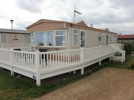 a static caravan with a wooden deck and railings at Seashore Holiday Park - Holiday Accommodation 5432, Great Yarmouth