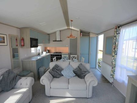 a living room with a sofa and kitchen area at Perran Sands - Holiday Accommodation 6251 Perranporth