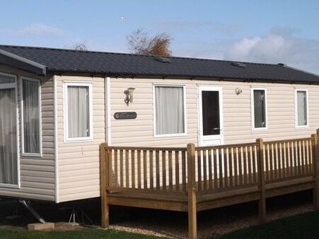 a mobile home with a wooden deck at Pinewoods Holiday Park - Holiday Accommodation 6322 Wells-next-the-Sea
