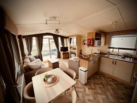 a living room and kitchen area with a sofa, dining table, and modern appliances at Devon Cliffs Holiday Park - Holiday Accommodation 6394 Exmouth