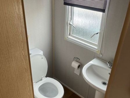 a small bathroom with a toilet and sink at Primrose Valley Holiday Park - Holiday Accommodation 6531, Filey