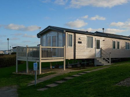 a caravan with a deck and steps at Reighton Sands Holiday Park - Holiday Accommodation 6835 in Filey