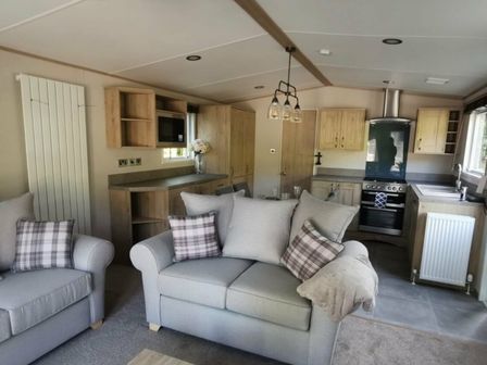 a living room with two sofas and a kitchen in White Acres Holiday Park - Holiday Accommodation 70 Nr Newquay