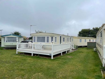 a mobile home with a deck surrounded by grass at Cherry Tree Holiday Park - Holiday Accommodation 7184 in Great Yarmouth