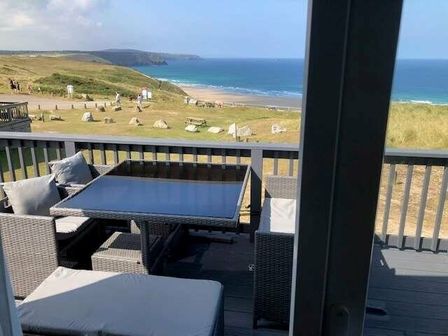 a patio with outdoor furniture overlooking the ocean at Perran Sands - Holiday Accommodation 7528, Perranporth, Cornwall, United Kingdom