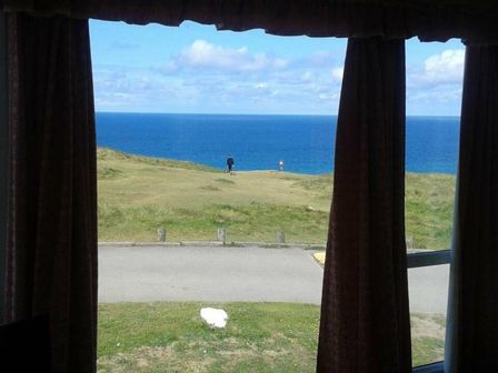 a view of the ocean from a window with curtains at Perran Sands - Holiday Accommodation 8131 in Perranporth