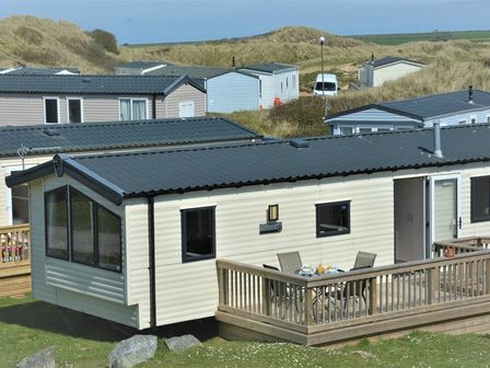 a holiday home with a wooden deck and outdoor seating at Perran Sands - Holiday Accommodation 8302, Perranporth