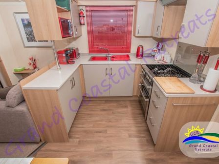 a kitchen with countertops, sink, stove, and cabinets at Grand Coastal Retreats