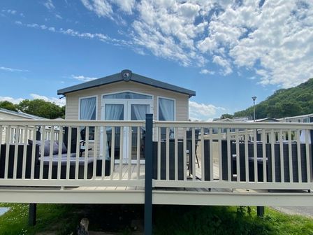 a holiday home with a deck and seating area at Quay West Holiday Park - Holiday Accommodation 8597 New Quay