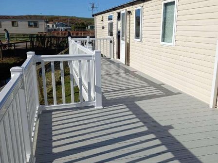 a wooden deck with white railing at Greenacres Holiday Park - Holiday Accommodation 9317 in Porthmadog