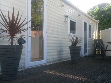 two planters and a chair on a deck outside a mobile home at Smytham Holiday Park - Holiday Accommodation 9561 Torrington