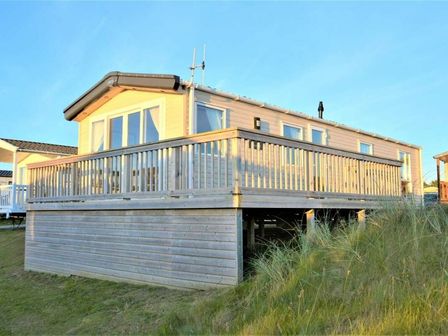 a holiday home on stilts with a wooden deck at Perran Sands - Holiday Accommodation 9657 Perranporth