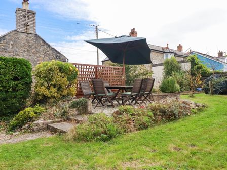 A garden with a table and chairs under an umbrella at Harford in