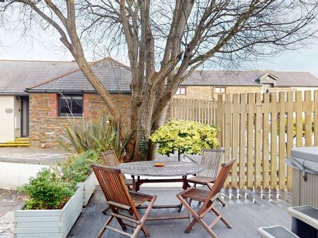 A garden with a table and chairs under a tree at Summerleaze Cottage 2 Spa in Bude