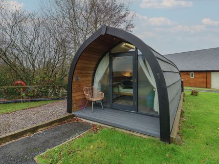 A cabin with a glass door and chair outside at Garden Lodge 1 Swansea
