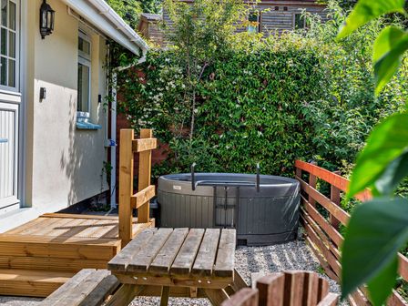 A garden with a hot tub and wooden furniture at Kernow Nook Spa, Perranporth