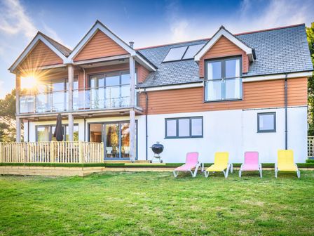 A house with a balcony and sun loungers at Nan's House Spa in Marhamchurch