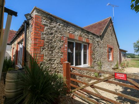 A stone house with a garden gate at The Old Barn in Stourton Caundle near Stalbridge