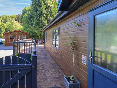 An outdoor view of a wooden house with decking and a planter at Evermore Lodge, 48 Calgarth Park, White Cross Bay, Windermere