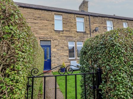 An exterior view of a house with a pathway and hedges at 23 Northumbria Terrace Amble