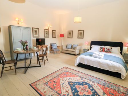 A bedroom with a bed, dining table, and sofa at Woodcock Studio in Andoversford near Cheltenham