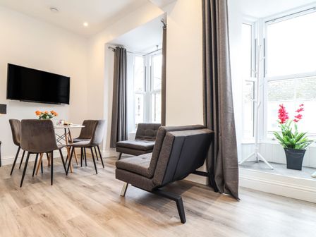 A living room with a sofa and dining table at Baker Chambers in Camborne