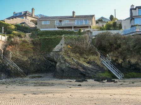 Houses on a cliff with stairs leading to the beach at Gilfach Goed Abersoch