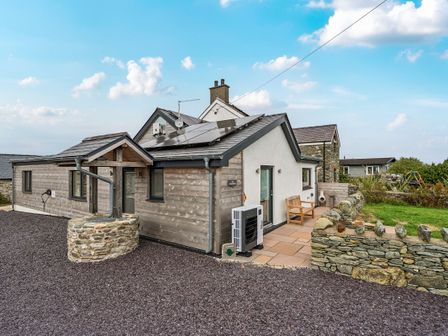 A house with solar panels and outdoor seating at Hen Penmynydd in Llanfwrog near Llanfachraeth