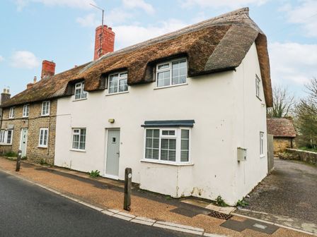 A house with a thatched roof and windows at Long Barn in Burton Bradstock