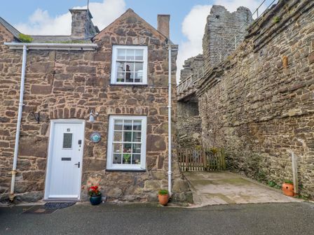A stone house with a front door and windows at Periwinkle Cottage in Conwy