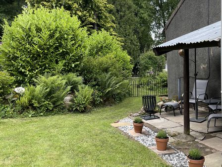 A garden with bushes and patio chairs at High Dyke Cottage