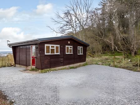 A chalet with gravel driveway and surrounding trees at Kilninver Chalet in