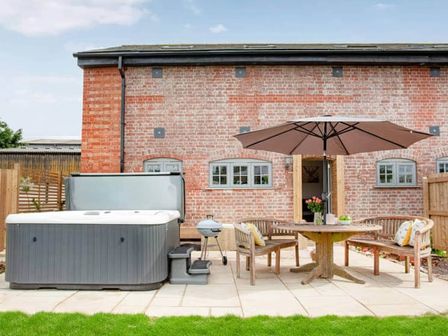 A garden with a hot tub and dining area at The Old Barn in Manchester