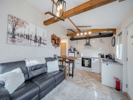 A living room with a couch and kitchen area at 38A in Bridlington