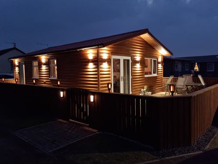 A cabin with a deck lit by lights at 50 Bridlington