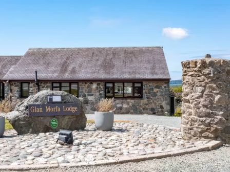 An outdoor view of Glan Morfa Lodge with a pebble pathway and stone features in Llangaffo