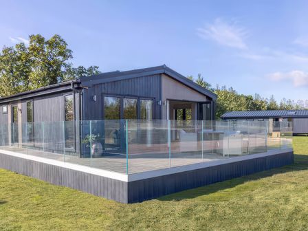 A lodge with decking and glass railing at Isca Lodge - With Decking - Lodge 1 Wombleton