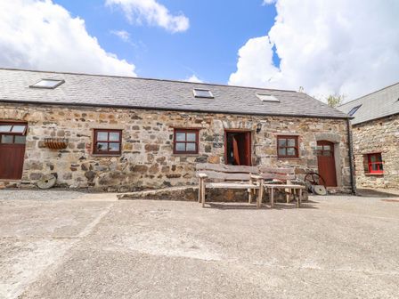 A stone building with wooden benches in an outdoor area at Ty Felin Newport