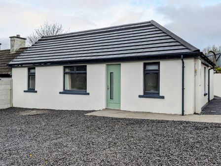 A house with a green door and gravel driveway at Duck Cottage in Caherciveen, County Kerry