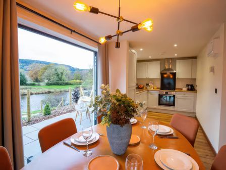 A dining room with a table set near a kitchen at Mountain View Cottage in Llanrwst