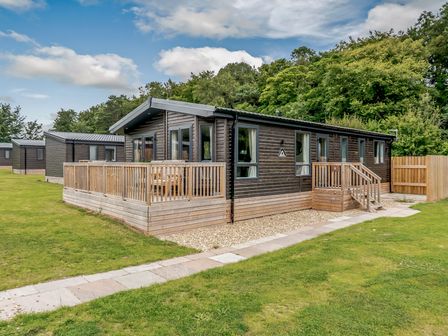 A wooden cabin with a deck and steps in an outdoor area at Elsham Lodge in Louth