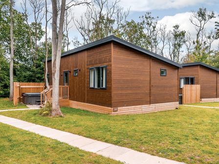 An outdoor area with wooden cabins and a hot tub at Stamford Spa (Pet) Louth