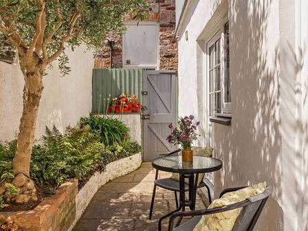 A garden with a table and chairs alongside plants at Ivy Cottage in Dartmouth